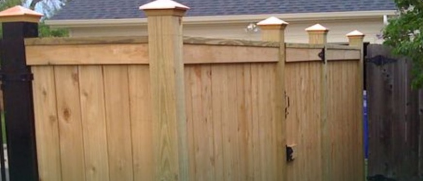 Copper post cap on a stained cedar fence post
